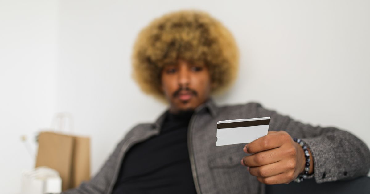Homem a segurar um cartão enquanto trata de pagamentos no telemóvel