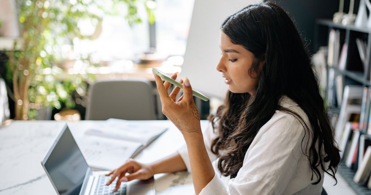 Mulher criando uma conta de e-mail no notebook e no celular em casa
