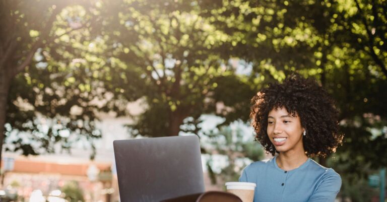 Mulher sorrindo ao usar o notebook com a conta protegida