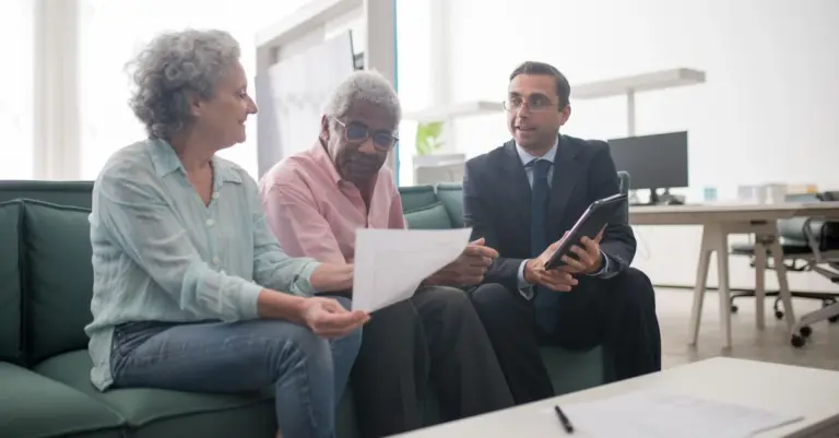 Casal idoso conversando com um consultor sobre documentos