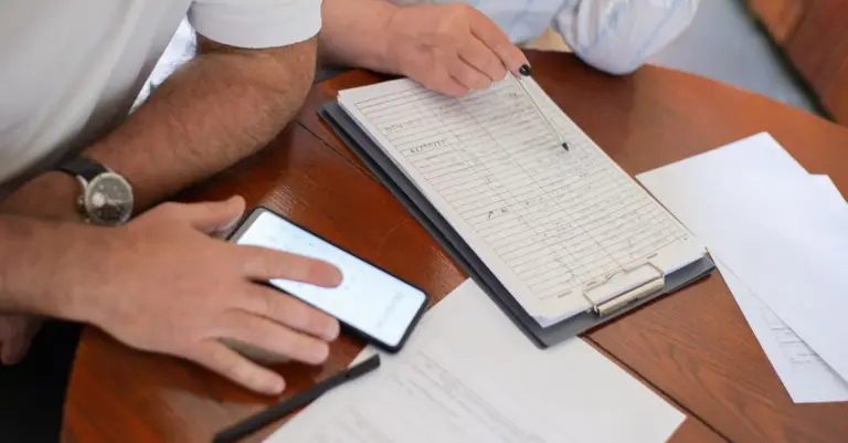 Casal revisando documentos e propostas na mesa com o celular