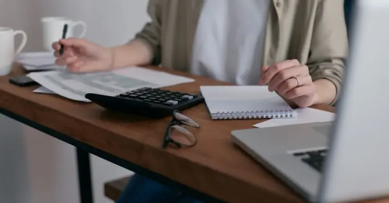 Pessoa organizando contas com calculadora