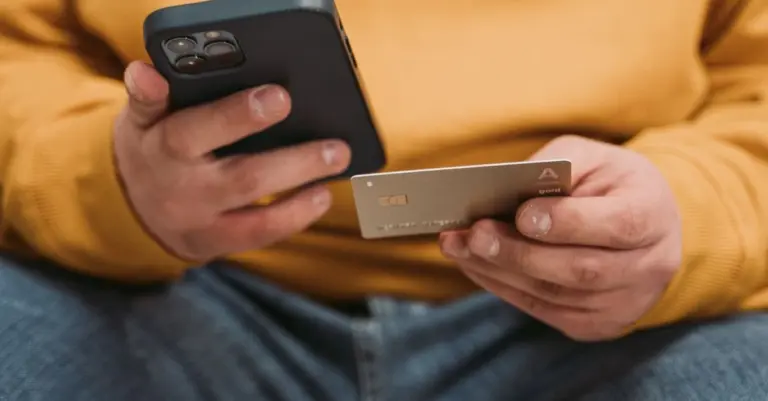 Mãos segurando celular e cartão de crédito