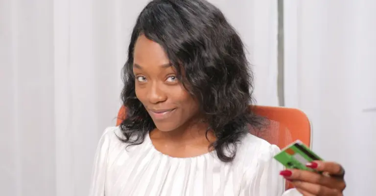 Mulher sorrindo segurando um cartão de crédito