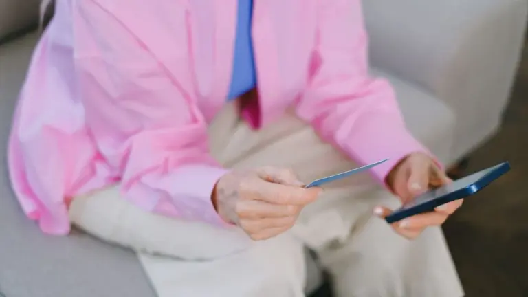 Pessoa segurando cartão e celular no sofá