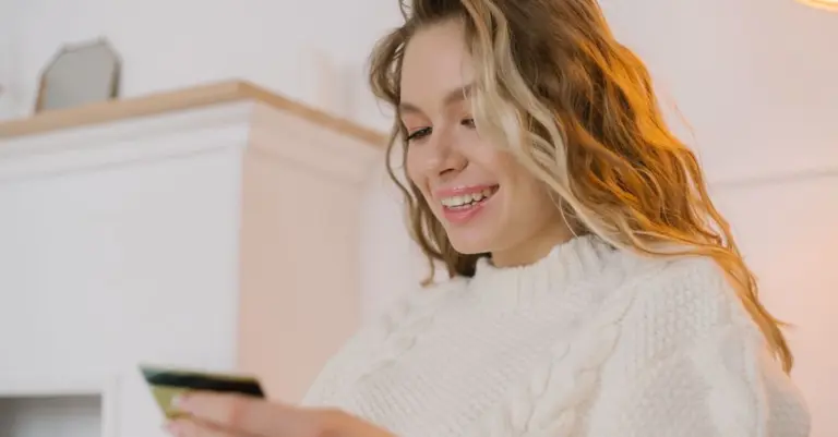 Mulher sorrindo segurando um cartão de crédito