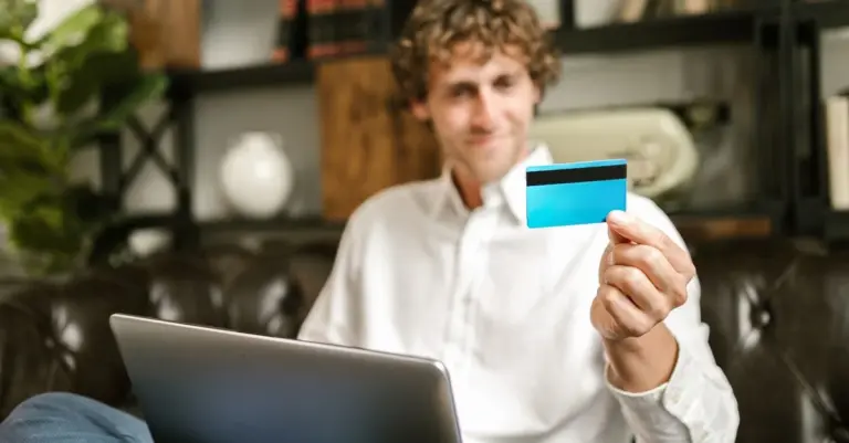 Homem sorrindo segurando um cartão de crédito