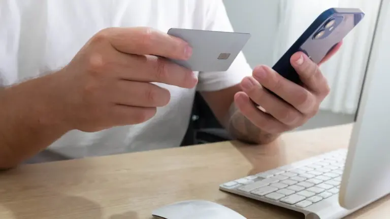 Pessoa segurando cartão de crédito e celular