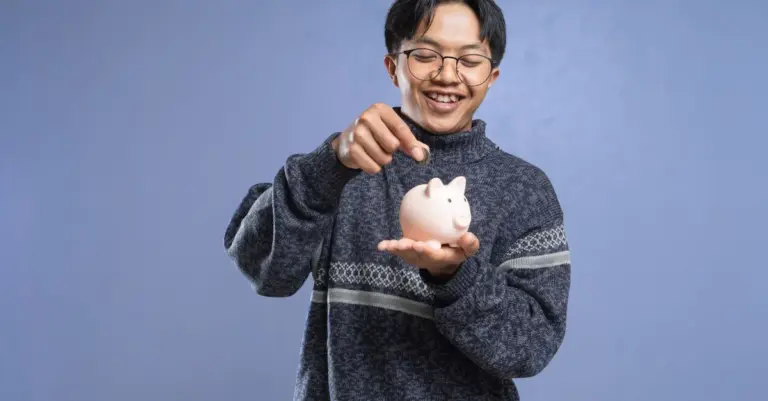 Homem sorrindo colocando moeda em um cofrinho