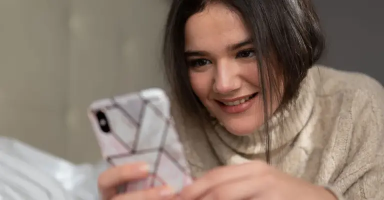 Mulher sorrindo ao ver o celular