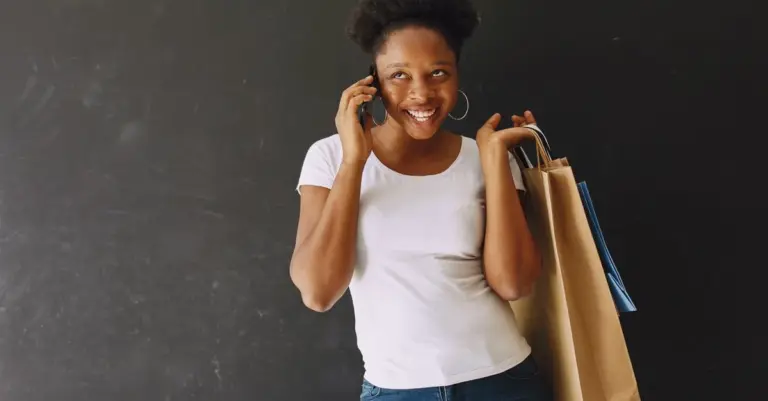 Mulher feliz com sacolas de compras e celular