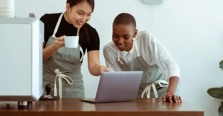 Microempreendedores de avental analisando o negócio no notebook
