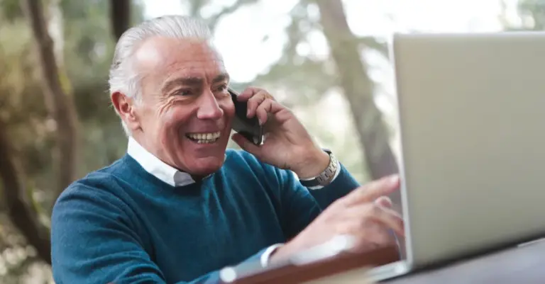 Homem sorridente ao telefone organizando benefício e trabalho pela conta