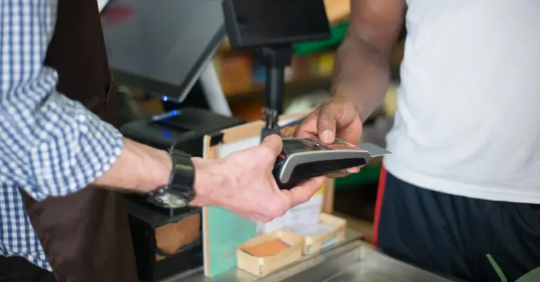 Cliente pagando com cartão na maquininha em uma loja