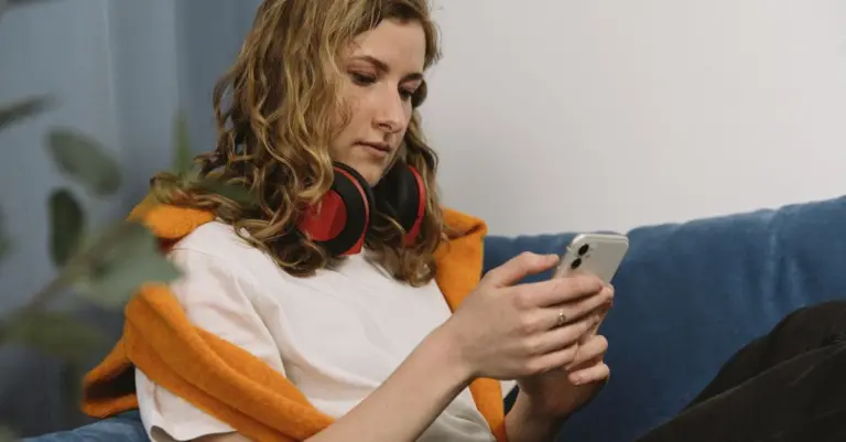 Jovem no sofá usando o celular em casa
