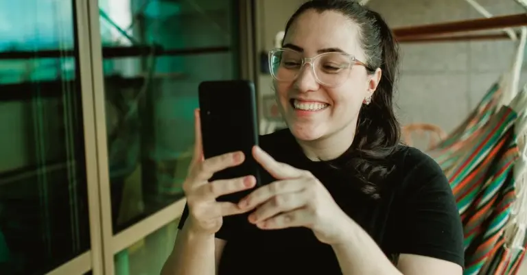 Mulher sorrindo usando o celular em casa
