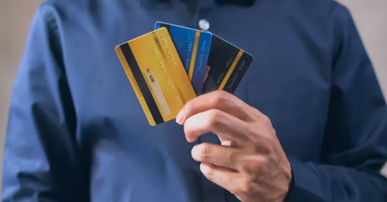 Pessoa segurando três cartões de crédito em leque