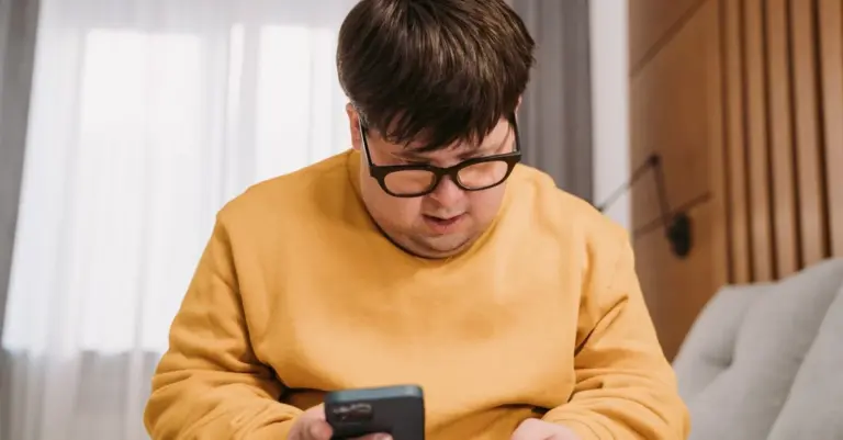 Homem usando o celular e segurando um cartão de crédito