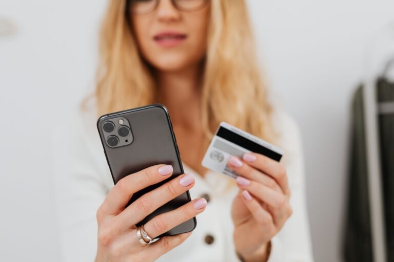 Mulher segurando cartão de crédito e celular