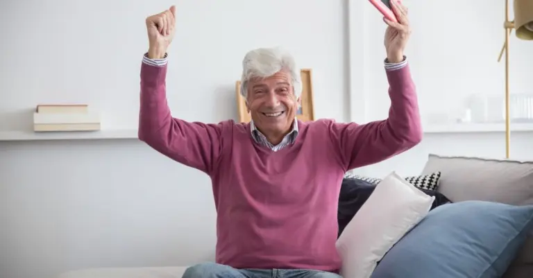 Senhor idoso feliz usando o celular em casa