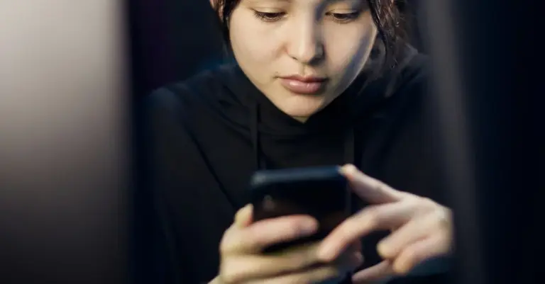 Mulher a olhar com atenção e cautela para o telemóvel, ilustrando o cuidado ao identificar tentativas de phishing bancário