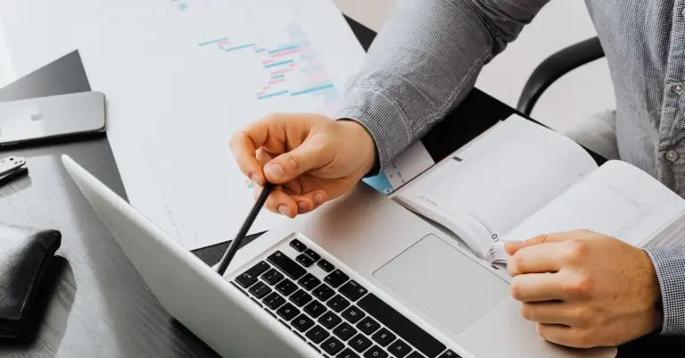 Pessoa a comparar dados e gráficos financeiros num laptop e documentos, ilustrando um ranking final de opções de crédito