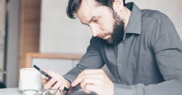 Homem a olhar atentamente para o smartphone, pensativo