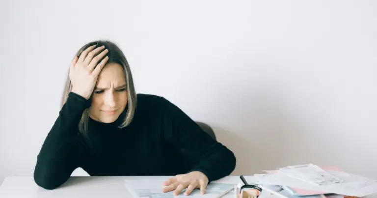 Mulher com aspeto preocupado a analisar papelada financeira numa mesa
