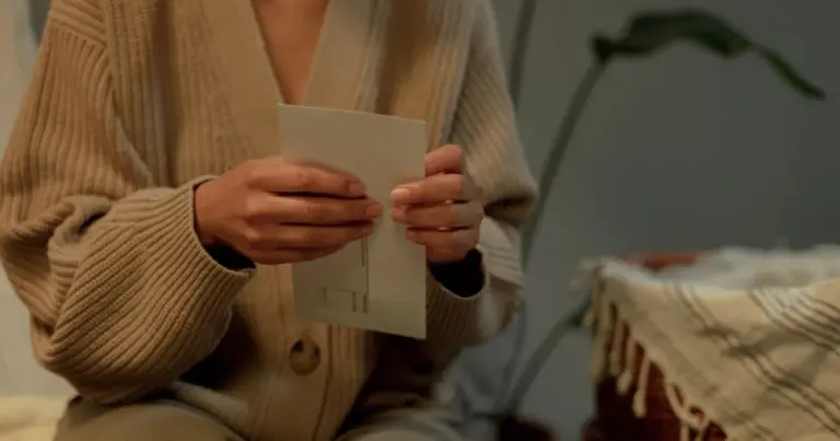 Pessoa a segurar uma carta em casa, com camisola quente
