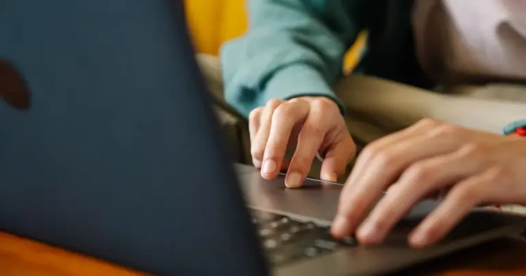 Pessoa a navegar na internet num portátil, a trabalhar numa secretária