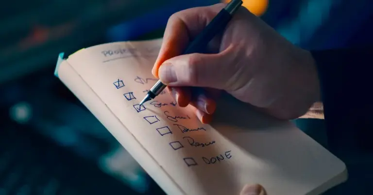 Mão a escrever uma checklist num caderno