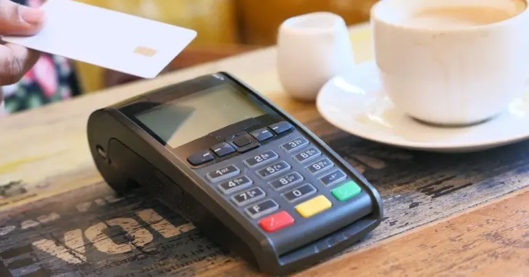 Cartão de crédito a ser aproximado de um terminal de pagamento junto a café