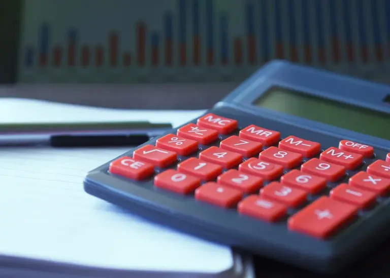 Calculadora vermelha com tecla de percentagem sobre secretária