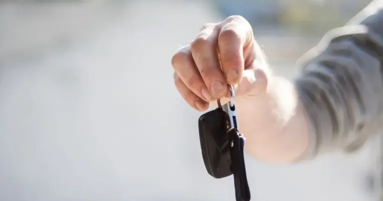 Mão a entregar uma chave de automóvel, aluguer de carro