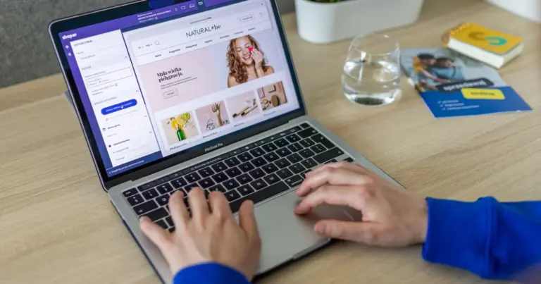 Mãos a digitar num portátil com um site de compras online aberto