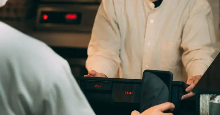 Pessoa a fazer um pagamento digital com o telemóvel num terminal de pagamento