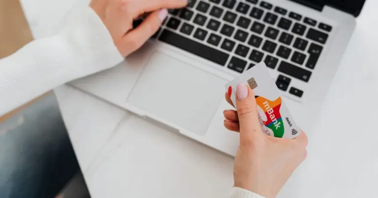 Pessoa a usar um portátil e a segurar um cartão para compra online