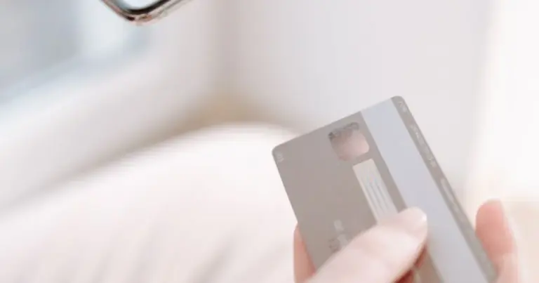 Mãos a segurar um telemóvel e um cartão para uma compra online