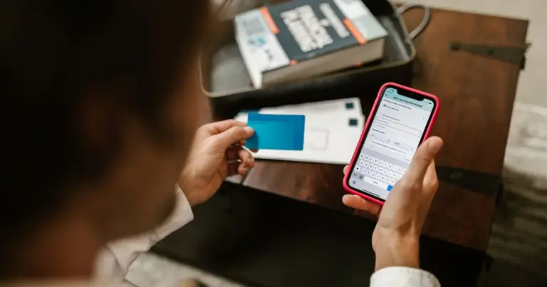 Pessoa a fazer um pagamento online usando o telemóvel e um cartão