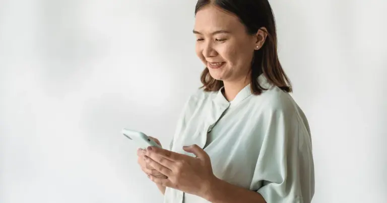 Mulher sorridente a usar o telemóvel em casa