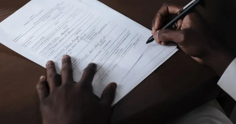 Mãos a assinar um documento oficial com caneta sobre uma mesa