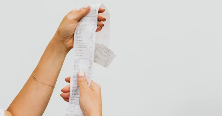 Mulher comparando recibos de compras para calcular cashback