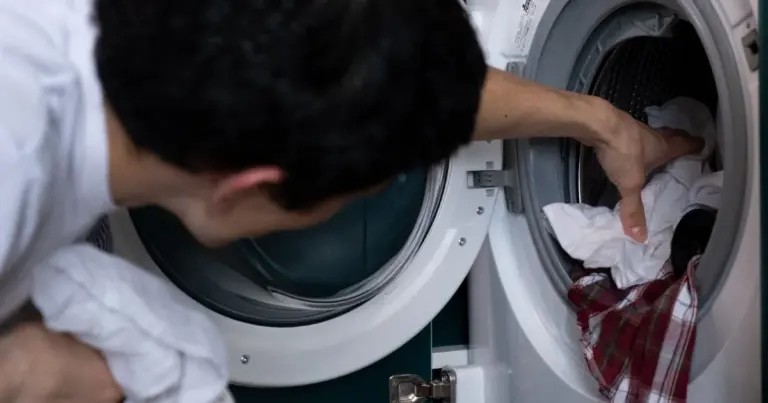 Homem a colocar roupa numa maquina de lavar