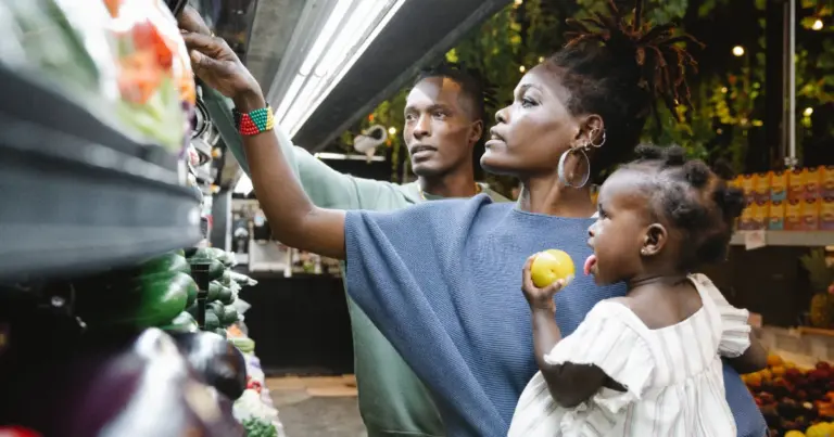 Familia a escolher fruta e legumes frescos num mercado