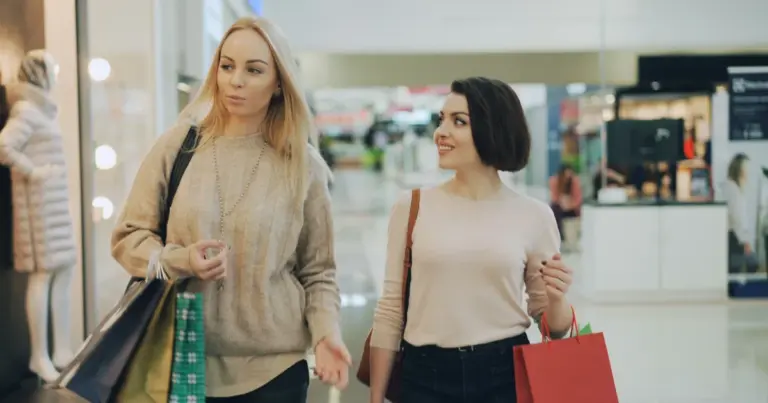 Duas mulheres com sacos de compras num centro comercial