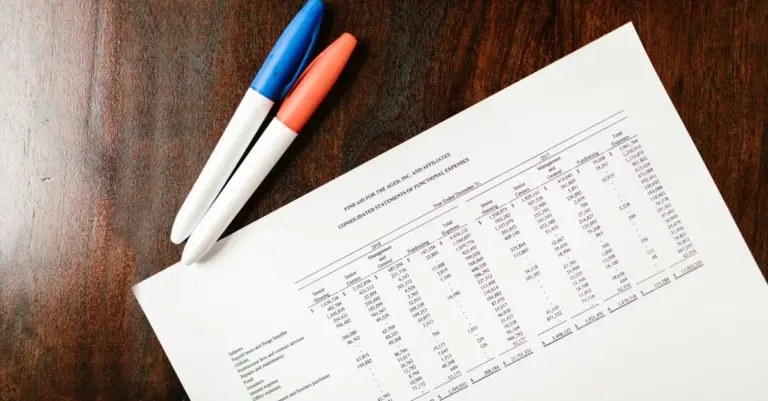 Documento com extrato financeiro e canetas coloridas, ilustrando a organização de dívidas para consolidação de crédito