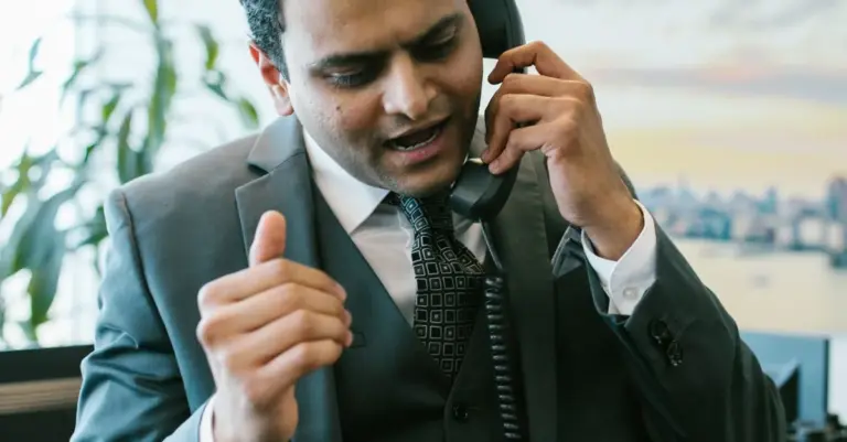Homem de negócios ao telefone com expressão séria, representando a negociação de uma dívida antes do incumprimento
