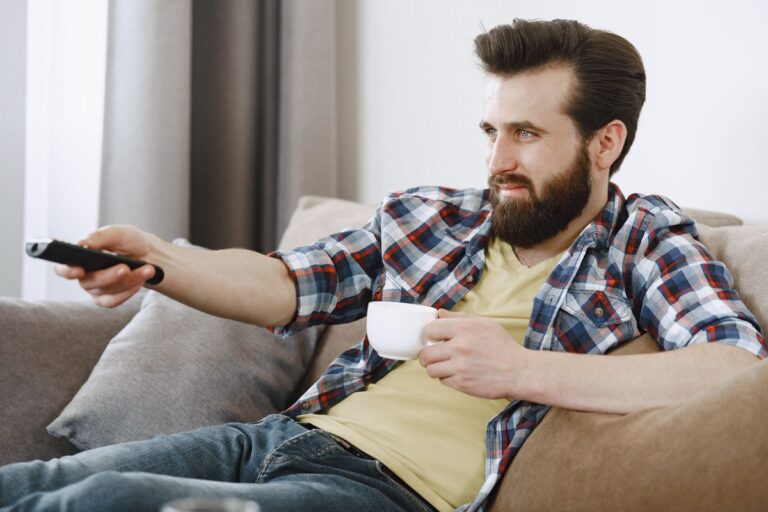 Pessoa assistindo televisão em casa com controle remoto